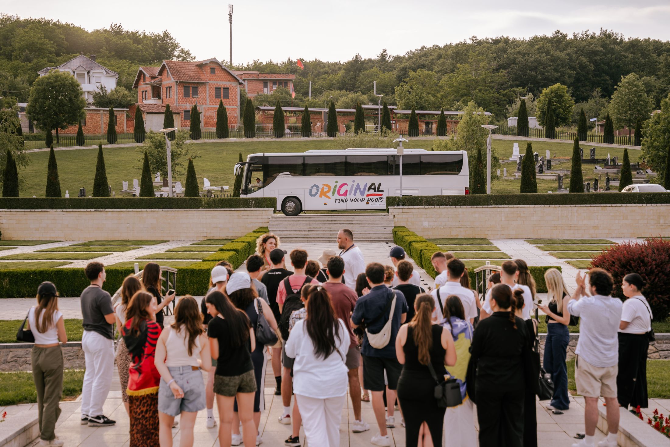 OriginAL participants gathered during a program visit, with the OriginAL bus behind them